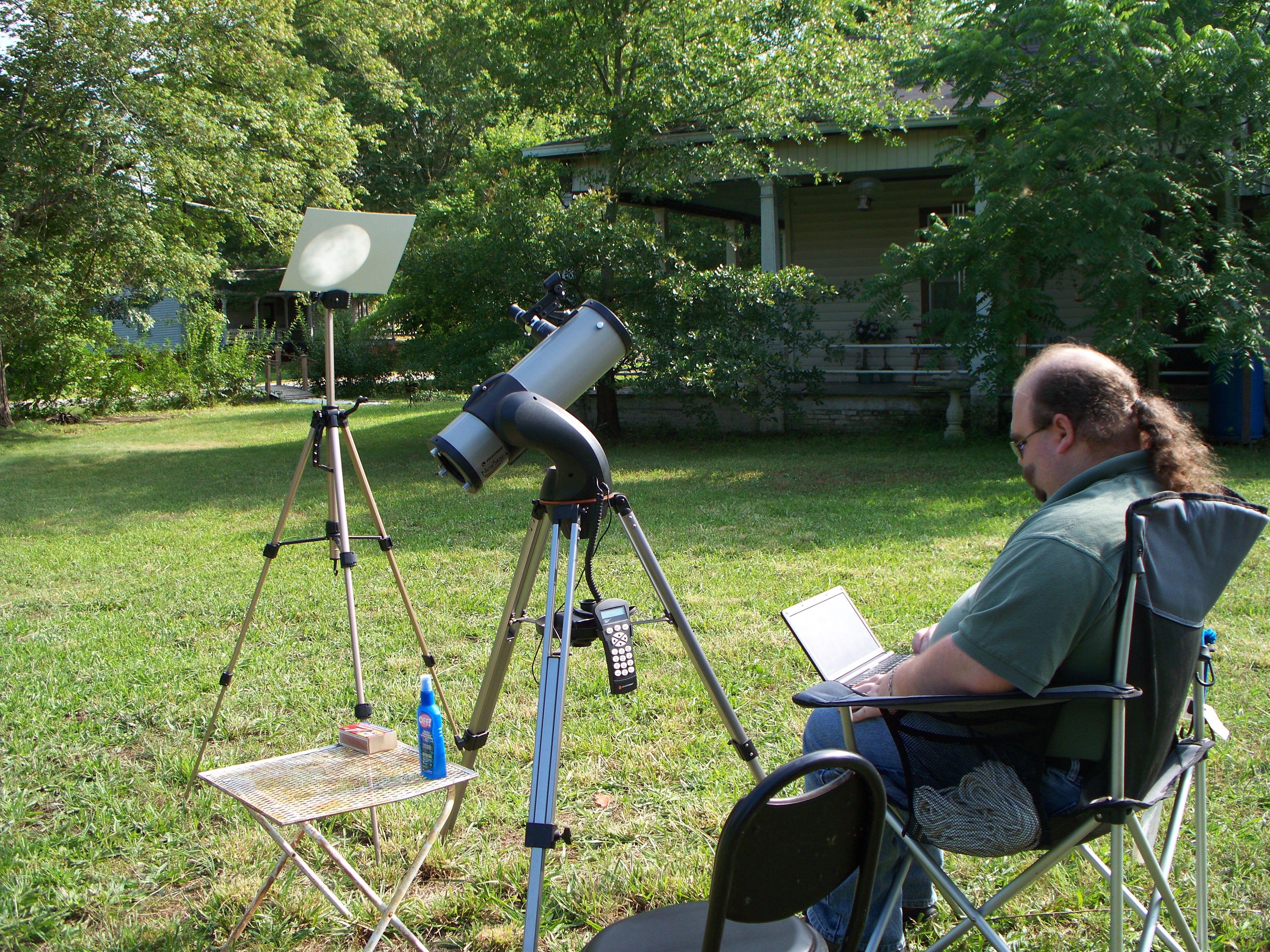 Geof streaming the NASA Edge broadcast and using twitter on the netbook while the telescope projects an image of the sun on a piece of white posterboard.