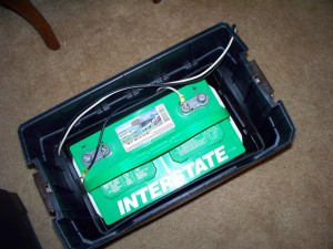 A large marine type battery inside the lower section of a rolling toolbox.