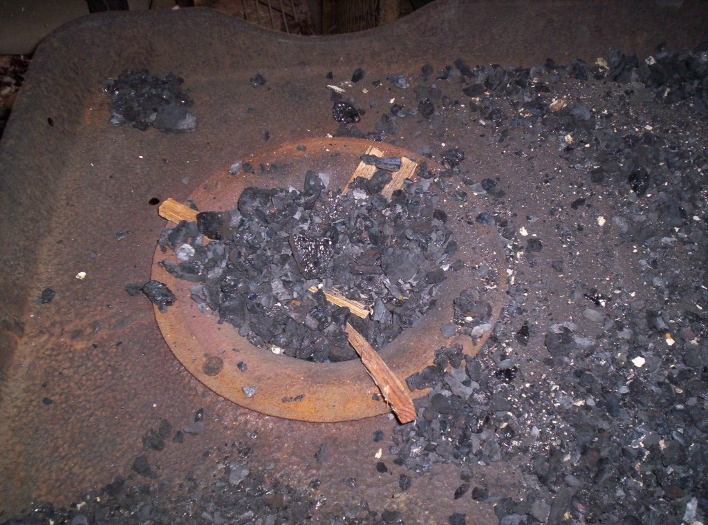 A pile of fat-wood fire starter sticks are under a pile of coal.