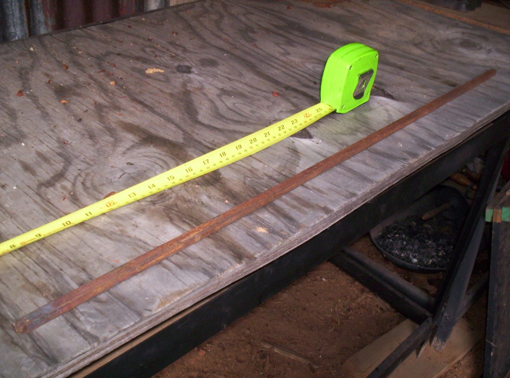 A piece of steel and a tape measure sit on a workbench.