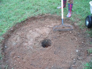 An area cleared of grass and topsoil with a drainage hole in the centre.
