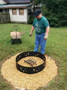 Geof looking at the fire pit area. Inside the fire ring is a fire grate.